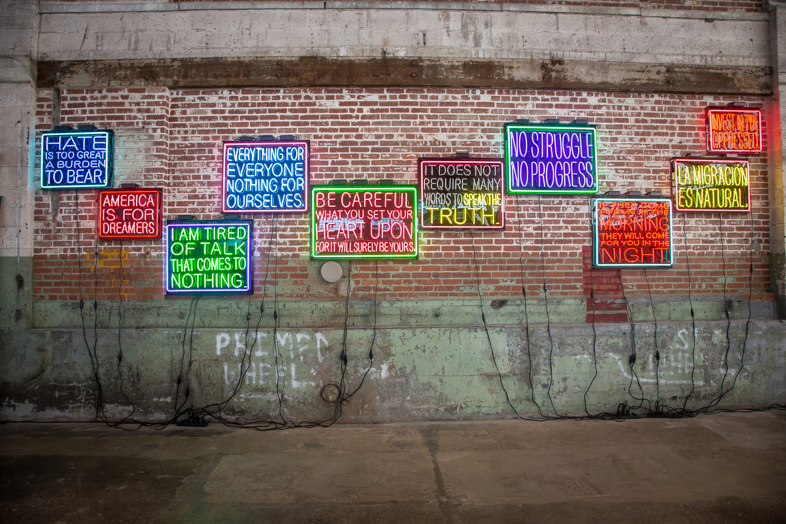 neon signs on a brick wall featuring inspirational phrases like no struggle no progress