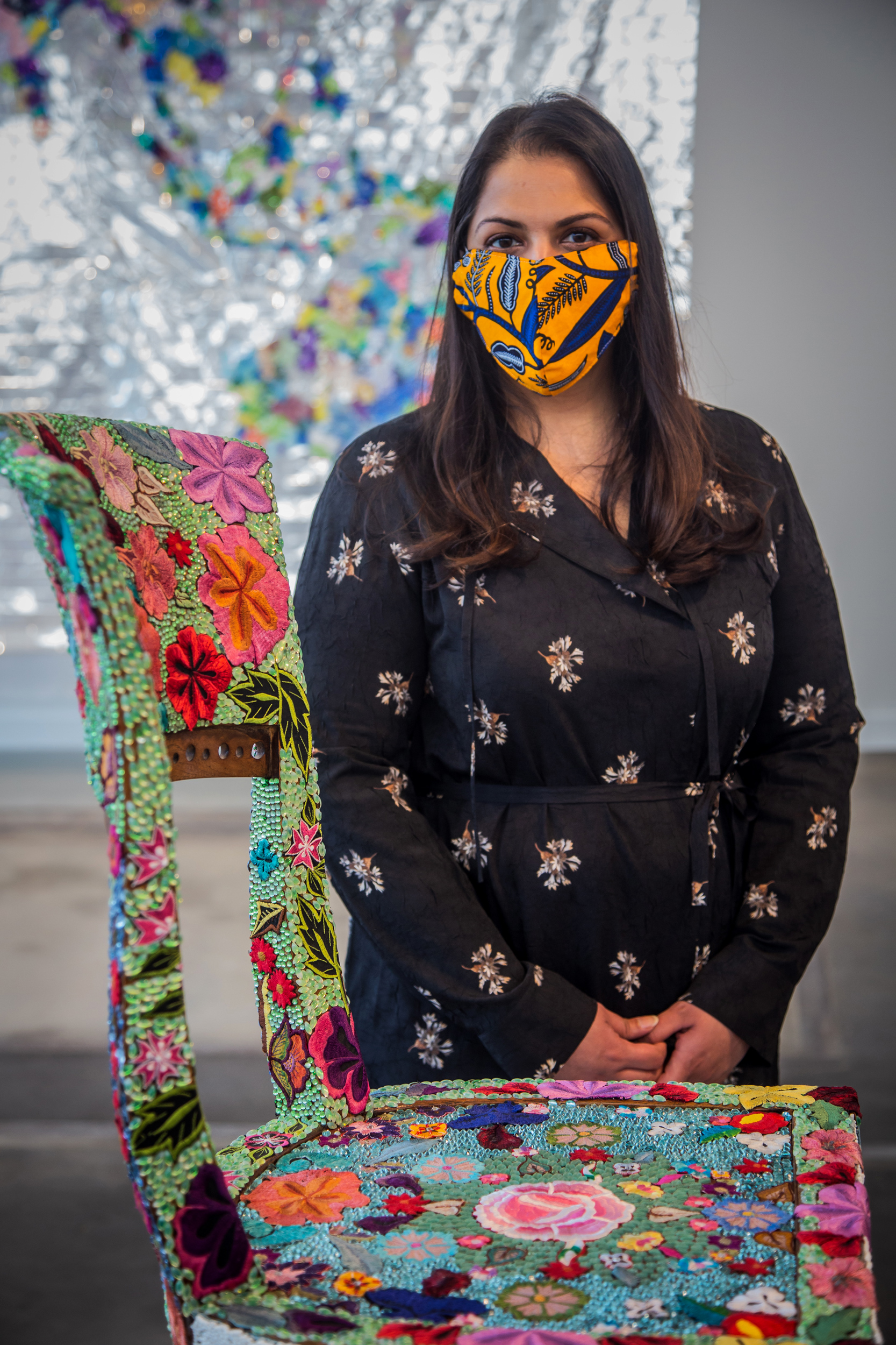 woman with a mask on standing next to the beaded chair