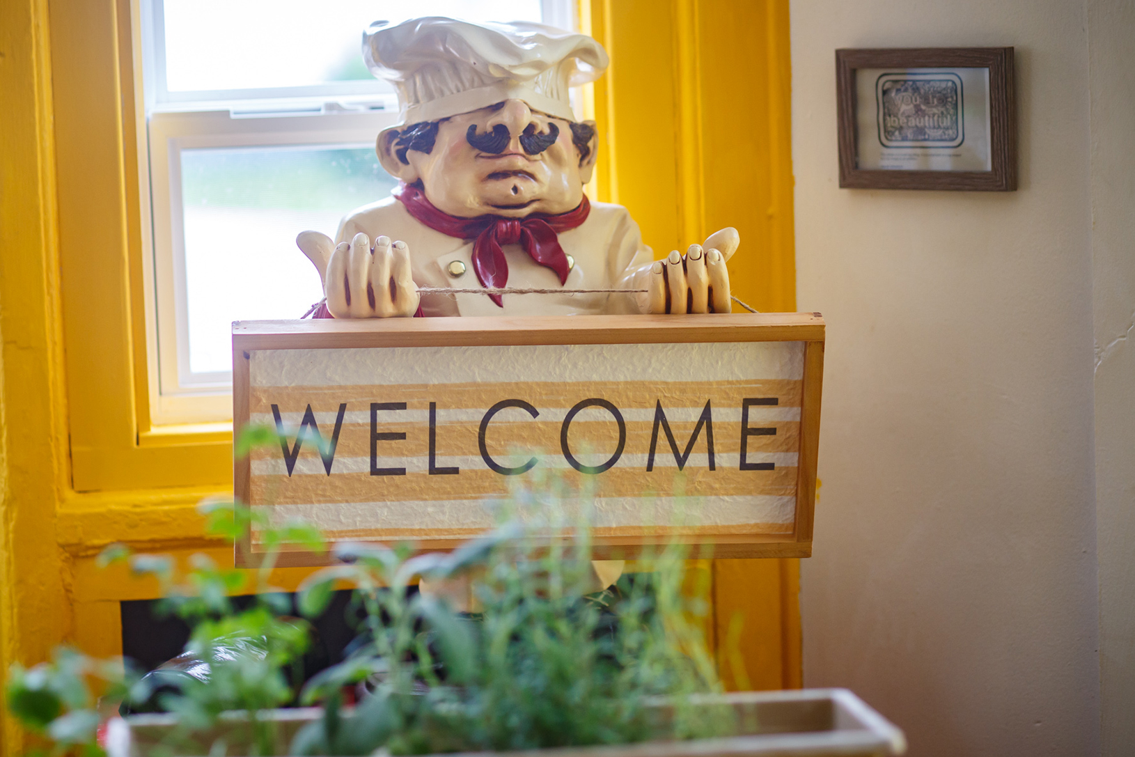 statue of a chef holding a welcome sign