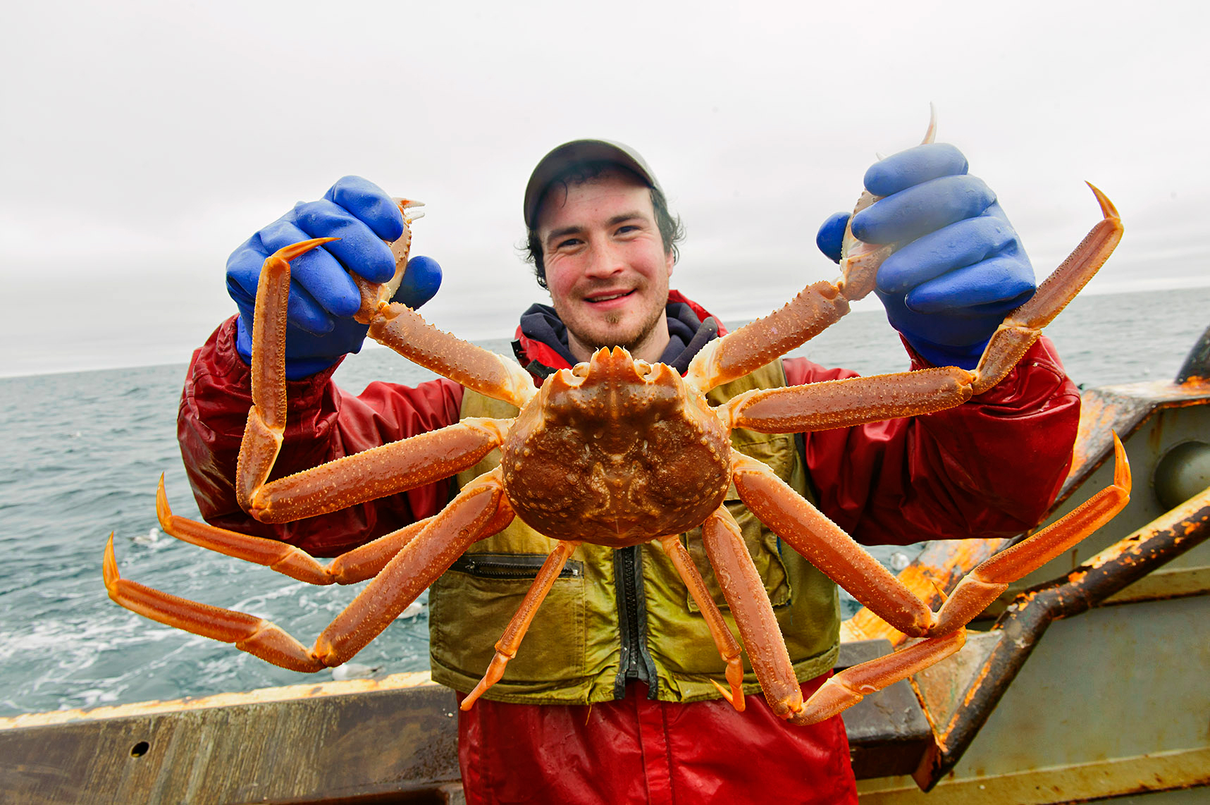 man on a boat holding a large crab