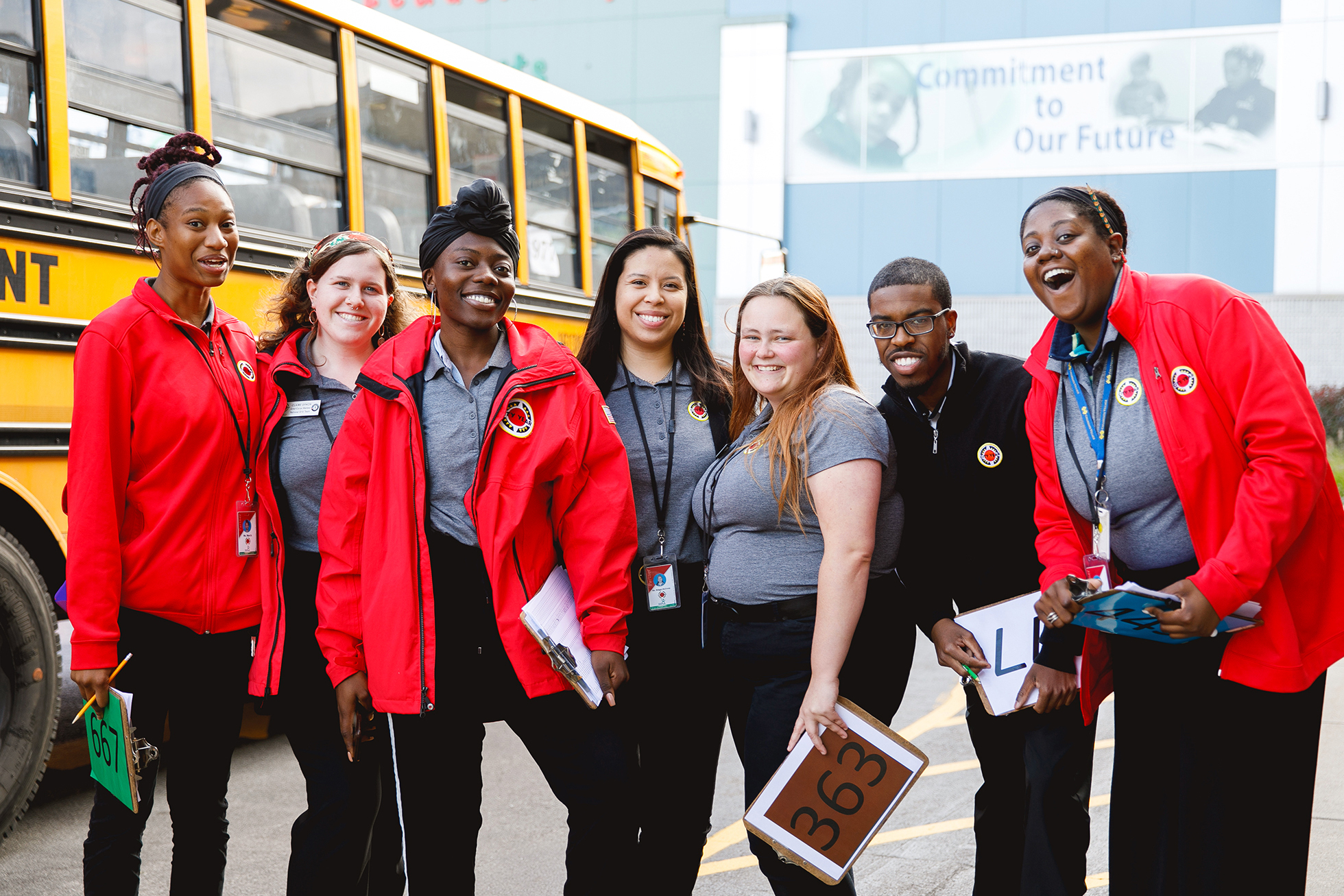 City Year's Americorps volunteers smiling in front of a school bus