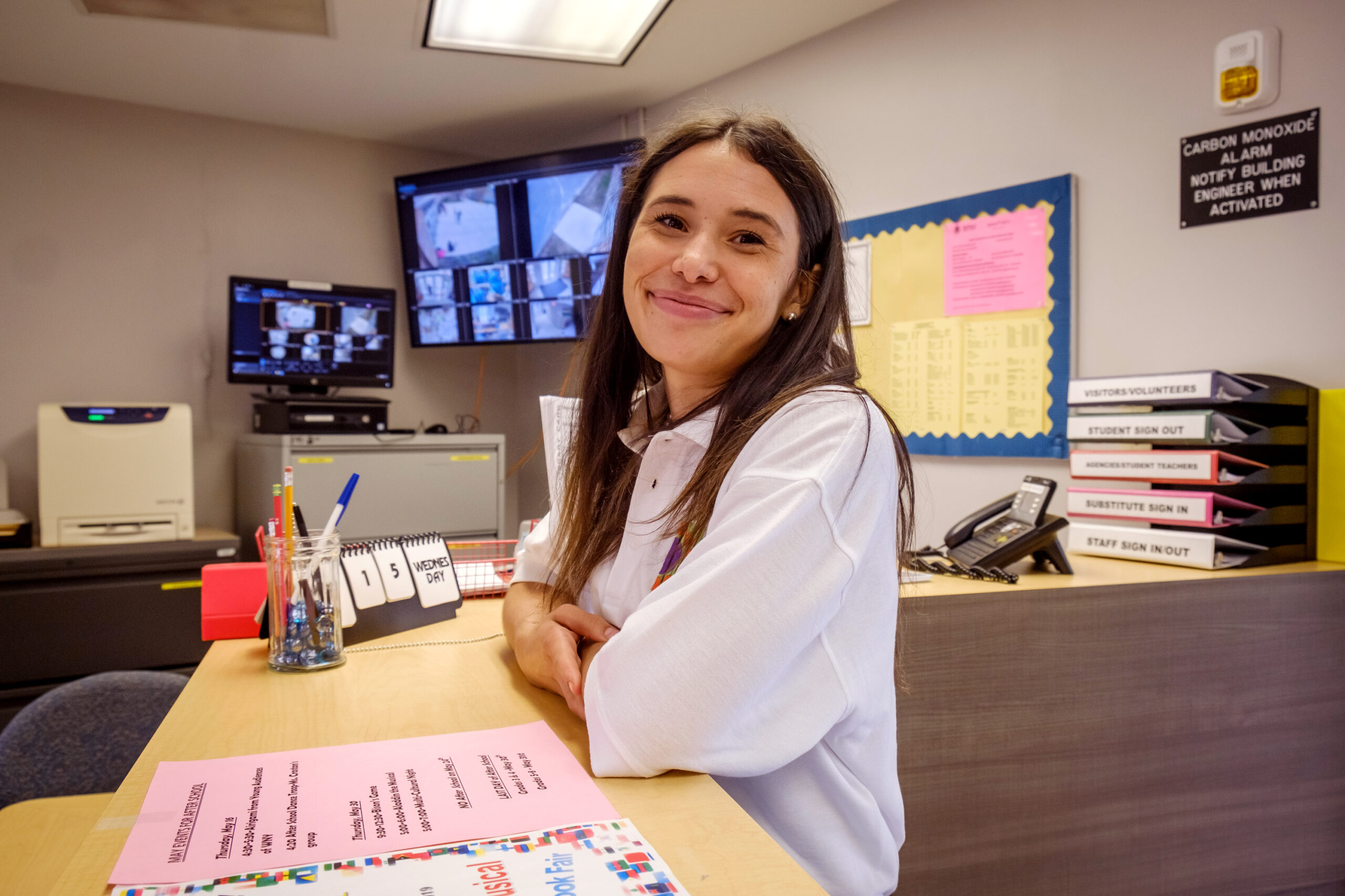 talia rodriguez standing at a reception desk smiling