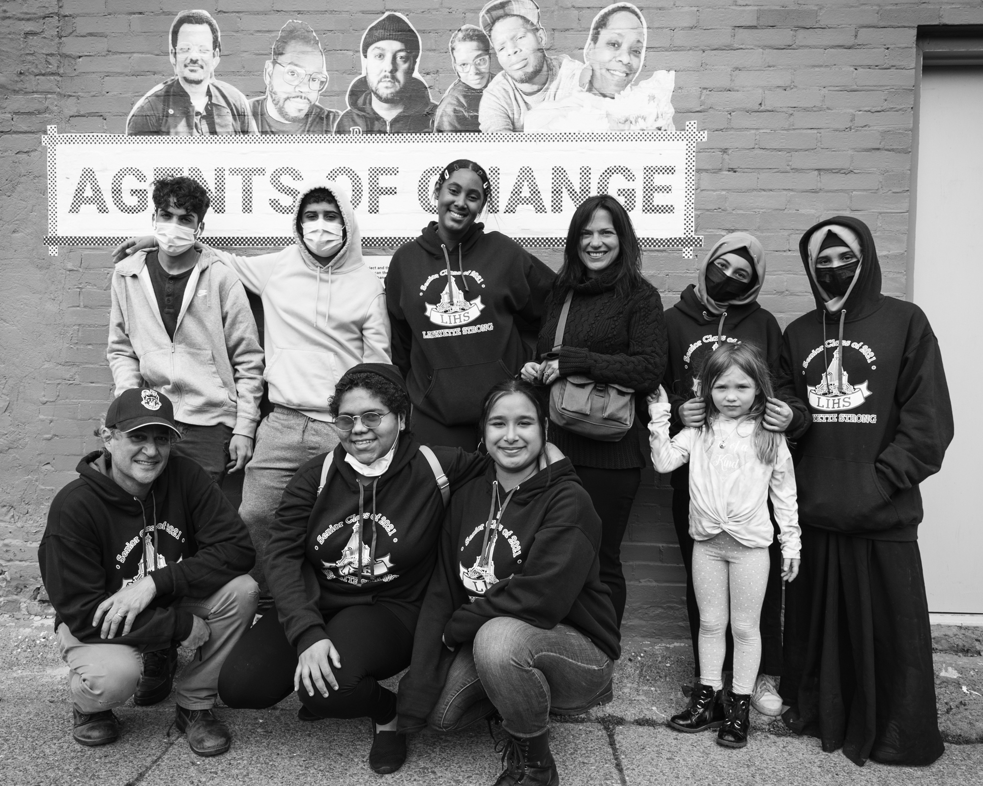black and white photo of people standing together in front of agents of change sign