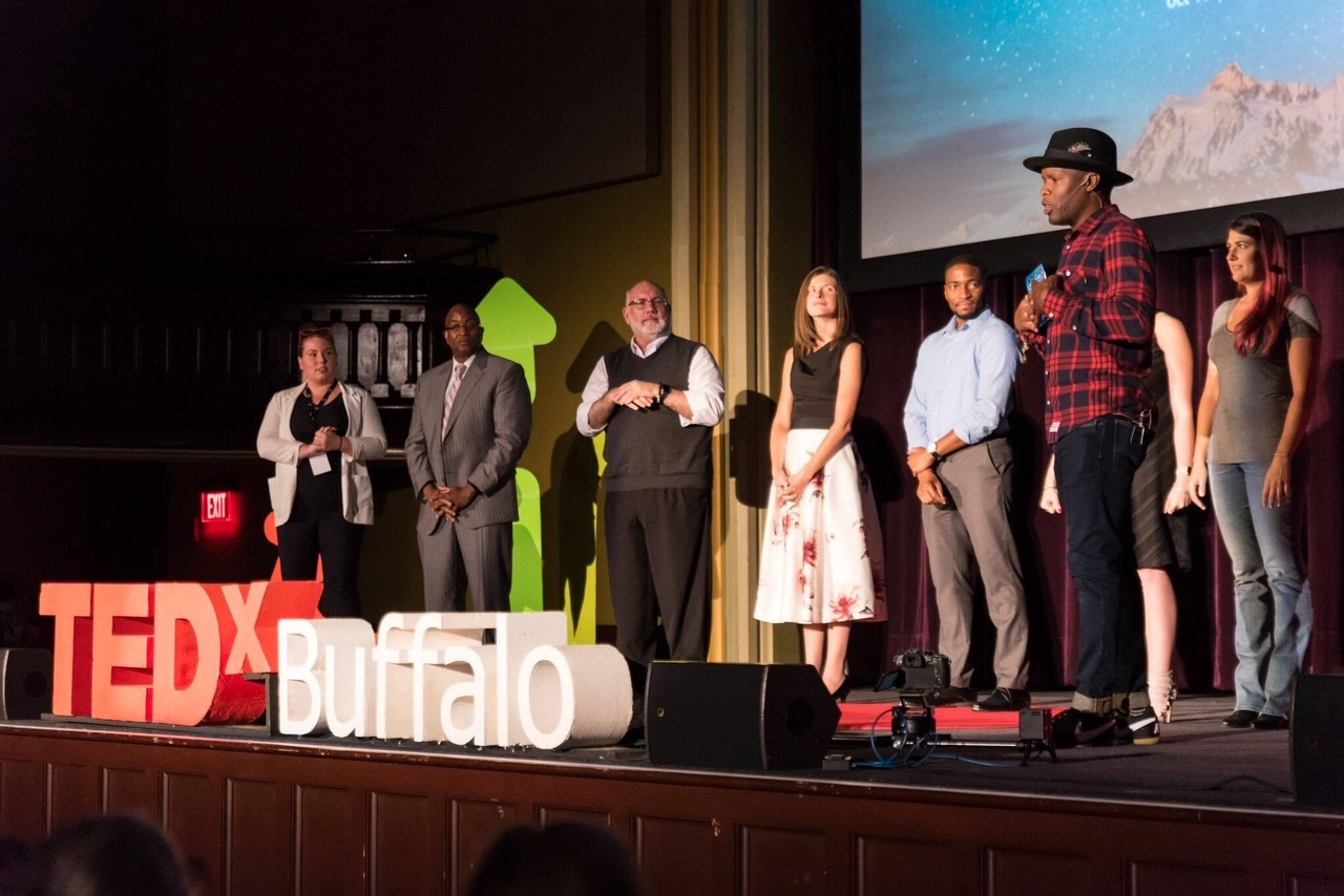 group of people onstage while a speaker is talking at tedx buffalo
