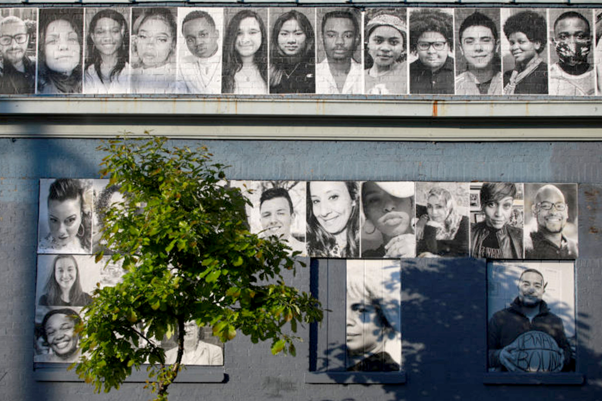 mural of people's portraits in black and white on the side of a brick building